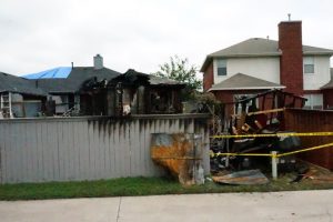 Home backyard exterior fire damage to fence and yard.