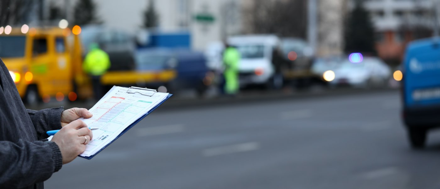 hands holding clip board with heavy equipment blurred in background.